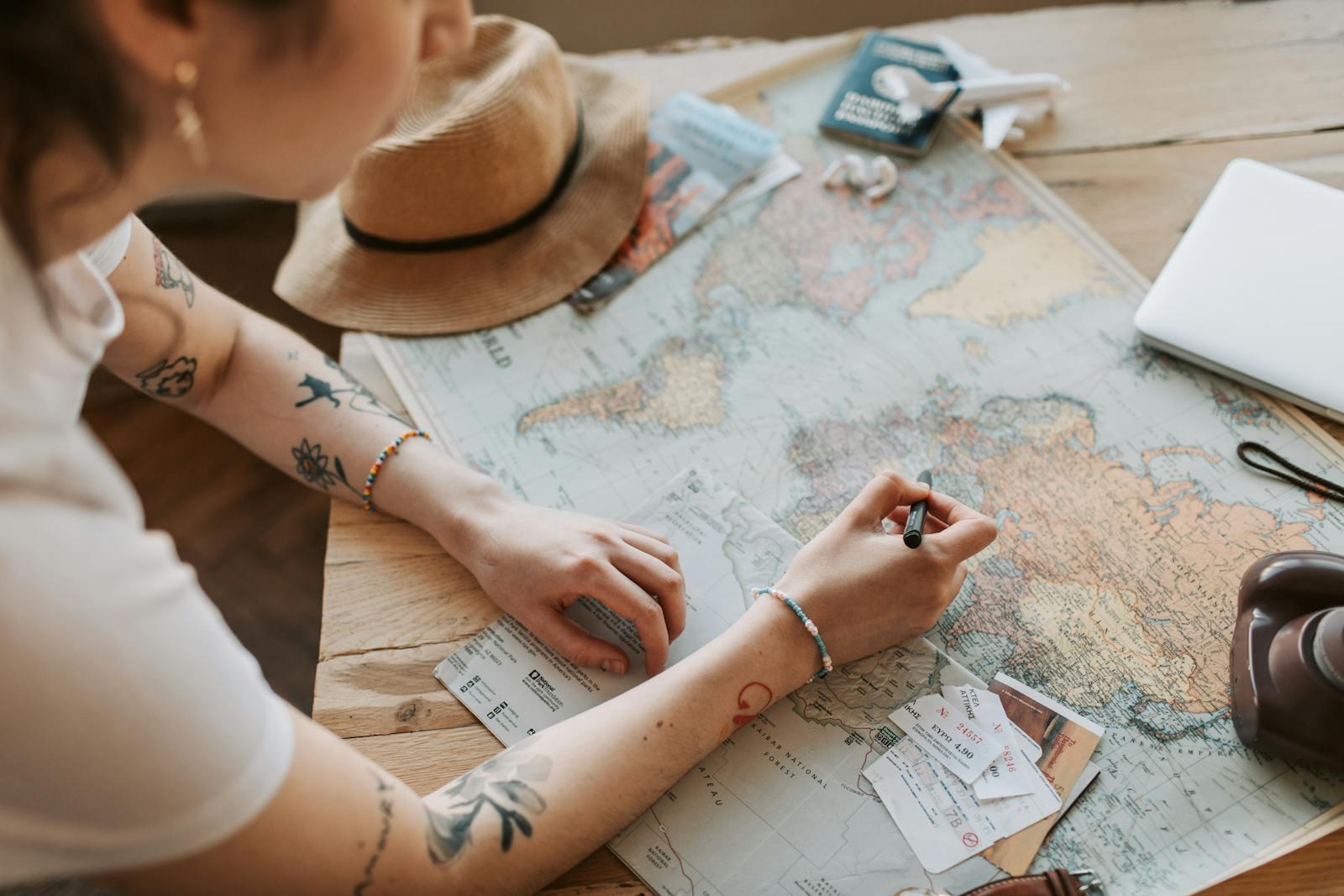 Photo by Vlada Karpovich Person planning a journey with a map, passport, and travel essentials on a wooden table.