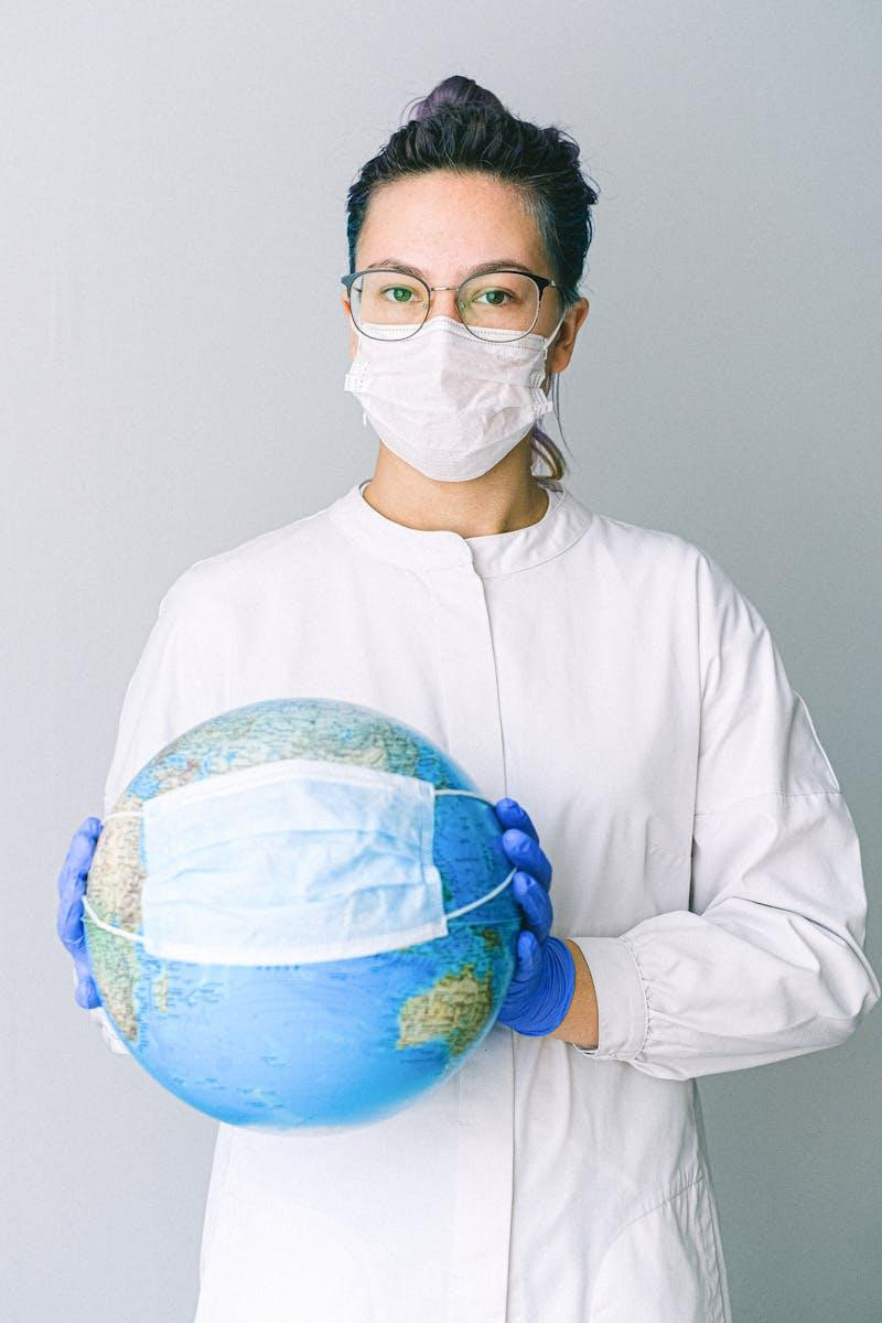 Photo by Anna Shvets Conceptual image of a doctor holding a globe with a mask, symbolizing global health. travel first aid kit