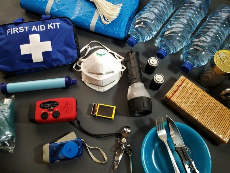 Travel First Aid Kits: Essential Items Every Traveler Needs 6 Flat lay of essential emergency survival kit items including first aid and water bottles.