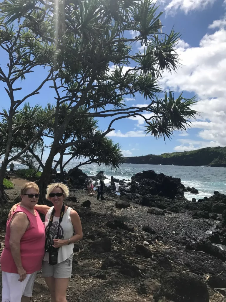Photo of Jennifer and her mother at a beach in hawaii with black rocks
