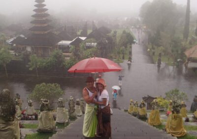 man and woman with red umbrella on steps of temple