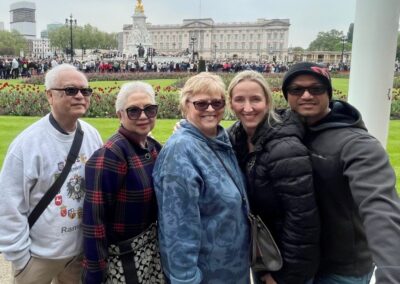 two men and three women in front of palace with lots of tourists