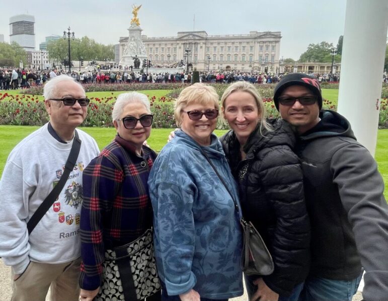 two men and three women in front of palace with lots of tourists