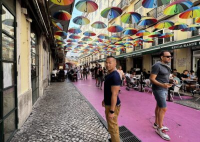 man standing on pink street with umbrellas overhead