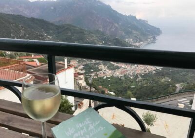 journal and glass of wine on table with view of town and coast