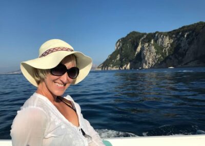 Jen with a a hat on a boat by a cliff