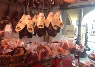 Hanging meats and table with cheeses in shop