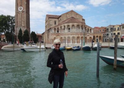 Woman standing by canal with boats and buildings