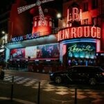 Vibrant night scene of the famous Moulin Rouge in Paris with neon lights and bustling atmosphere.