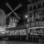 A classic black and white capture of the iconic Moulin Rouge at night in Paris, France.