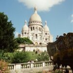Sacre Coeur Basilica in Paris on a bright day with lush greenery and carousel.