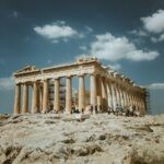 Low angle shot of the Parthenon, Athens, with tourists against a clear blue sky.